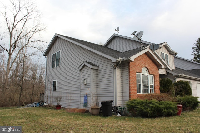 view of home's exterior featuring brick siding, a lawn, and a shingled roof