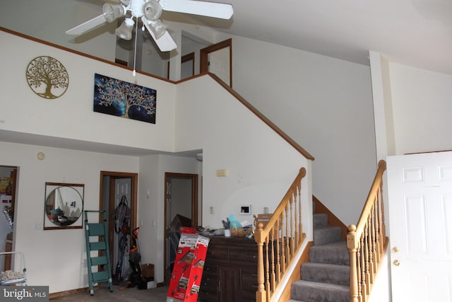 stairs with a ceiling fan and a towering ceiling