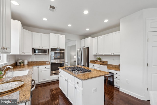 kitchen featuring a kitchen island, light stone countertops, stainless steel appliances, and a sink