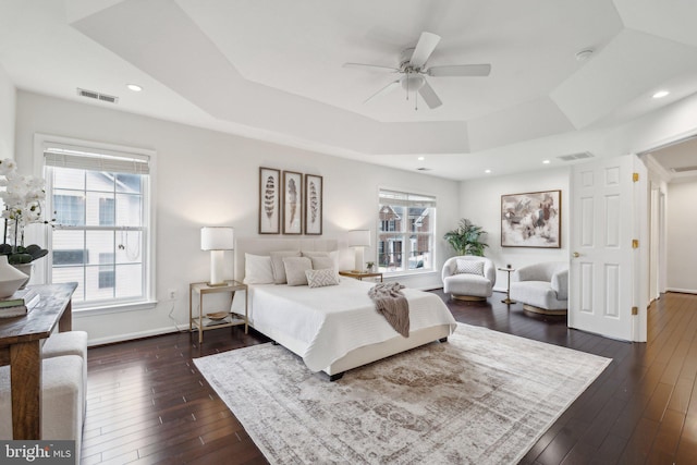 bedroom with baseboards, visible vents, dark wood-style floors, and a tray ceiling