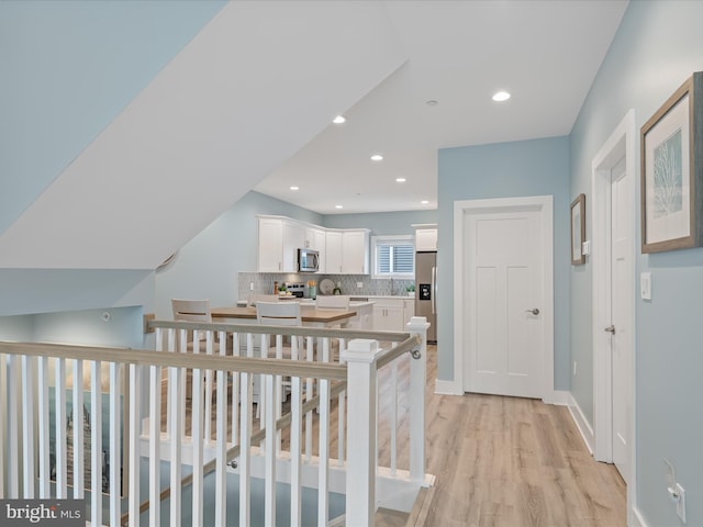corridor featuring a sink, light wood finished floors, and recessed lighting