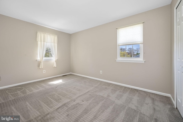 carpeted empty room featuring baseboards