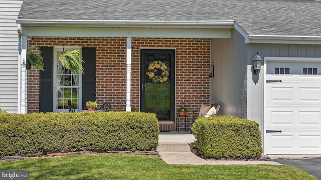 doorway to property featuring brick siding, roof with shingles, and a garage
