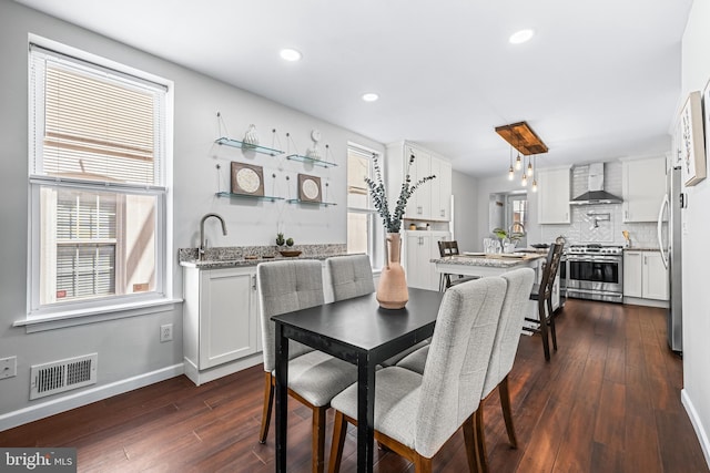 dining area with wet bar, visible vents, baseboards, dark wood-style floors, and recessed lighting