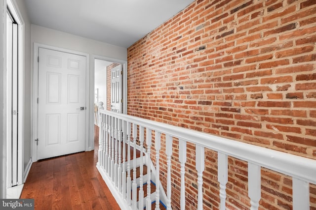 hall featuring wood-type flooring and brick wall