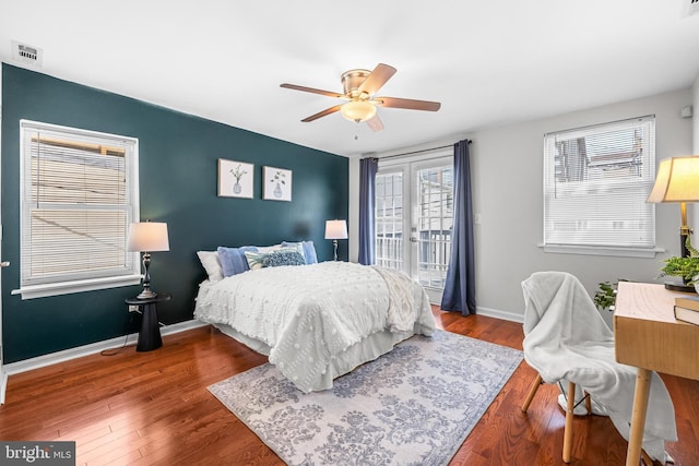 bedroom featuring wood finished floors, ceiling fan, baseboards, access to outside, and visible vents