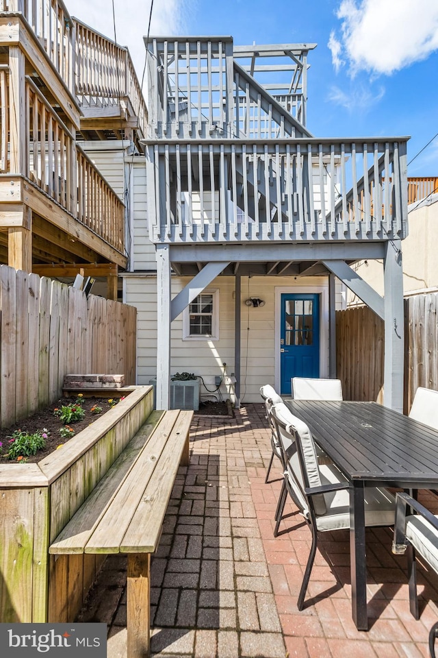 back of house with a wooden deck, a patio area, a fenced backyard, and outdoor dining area