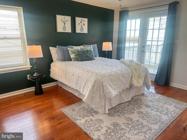 bedroom featuring wood finished floors, baseboards, access to exterior, and multiple windows
