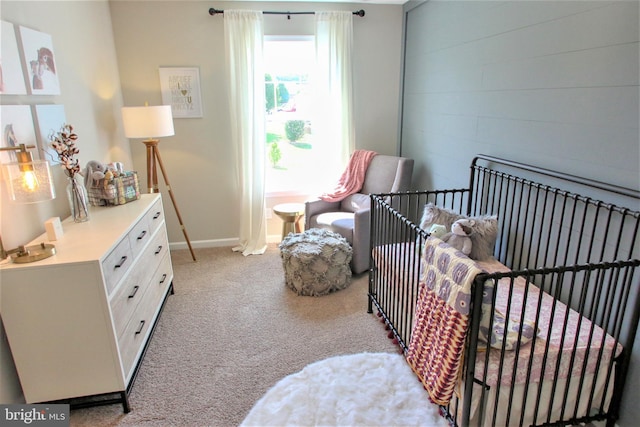 bedroom with a crib, baseboards, and carpet flooring