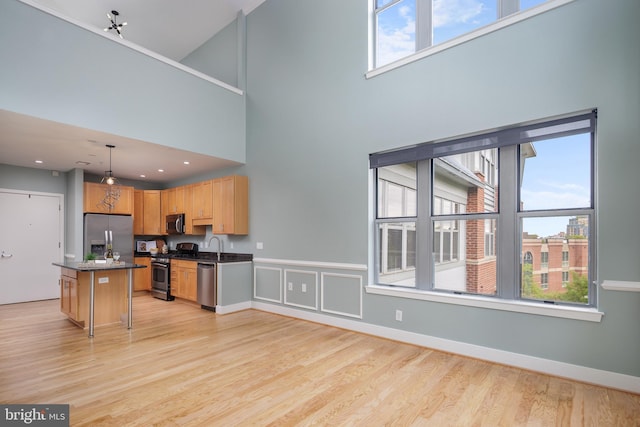 kitchen featuring dark countertops, a wealth of natural light, appliances with stainless steel finishes, and light wood finished floors