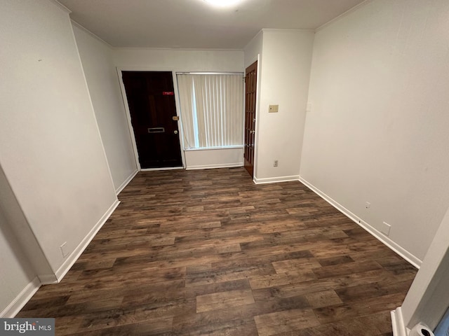 interior space featuring baseboards, ornamental molding, and dark wood-type flooring