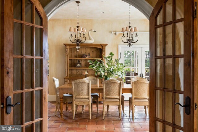 dining space with french doors, arched walkways, and a notable chandelier