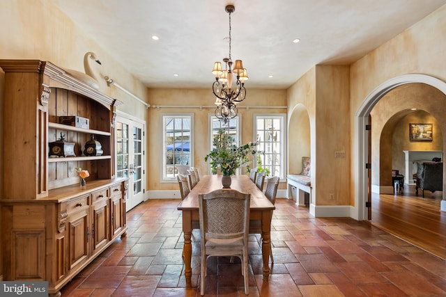 dining room featuring arched walkways, a notable chandelier, recessed lighting, and baseboards