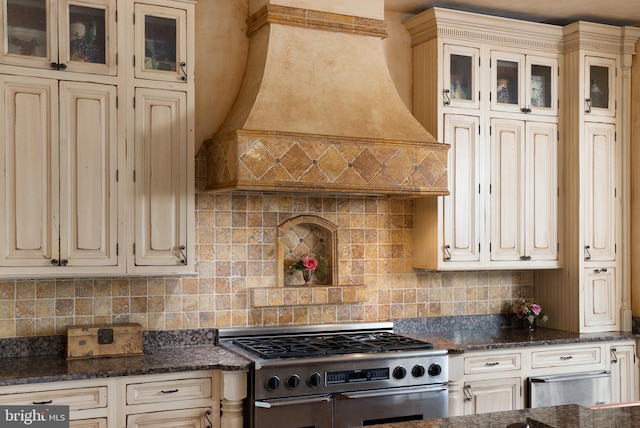 kitchen with double oven range, cream cabinetry, glass insert cabinets, and custom range hood