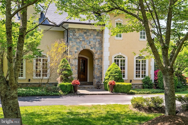 view of exterior entry featuring stucco siding and stone siding