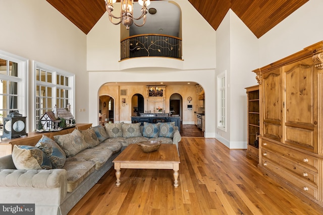 living area featuring a notable chandelier, wooden ceiling, high vaulted ceiling, hardwood / wood-style flooring, and arched walkways