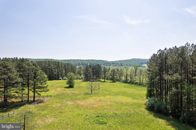 view of yard with fence, a rural view, and a view of trees