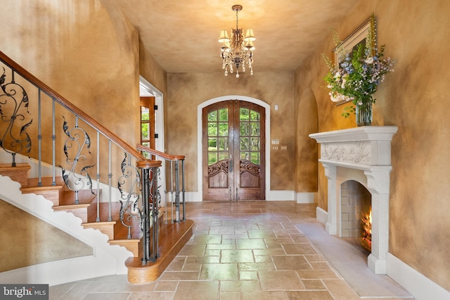 foyer featuring an inviting chandelier, stairs, french doors, and stone tile flooring