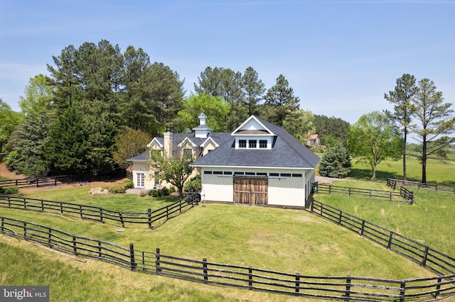 exterior space featuring a detached garage, driveway, an outbuilding, an exterior structure, and a rural view