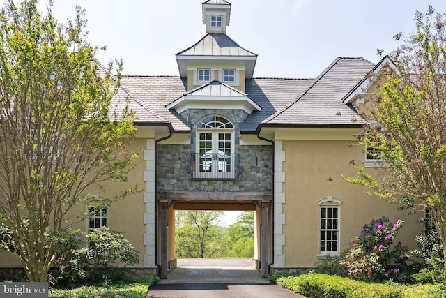 exterior space featuring stone siding, stucco siding, a standing seam roof, and metal roof