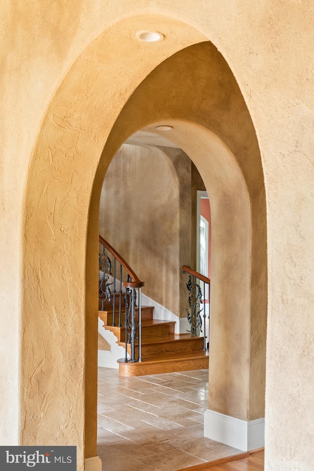 interior space with baseboards, arched walkways, and a textured wall