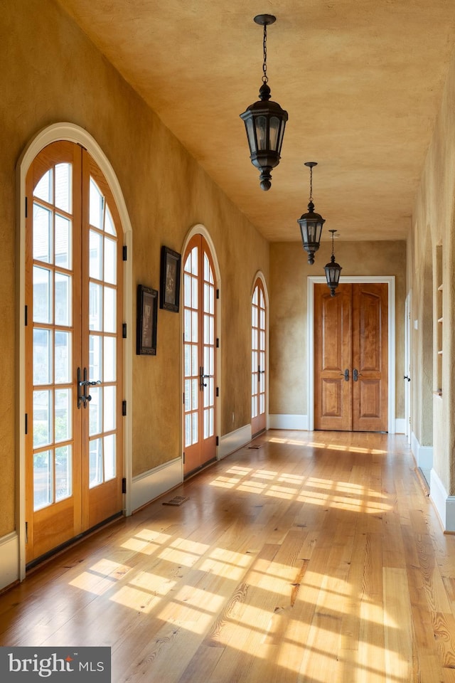 interior space with baseboards, french doors, and wood finished floors