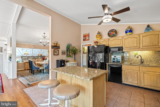 kitchen featuring a sink, light brown cabinetry, black appliances, vaulted ceiling, and backsplash