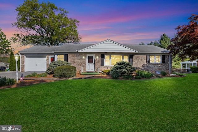 ranch-style home with a yard, concrete driveway, brick siding, and a garage