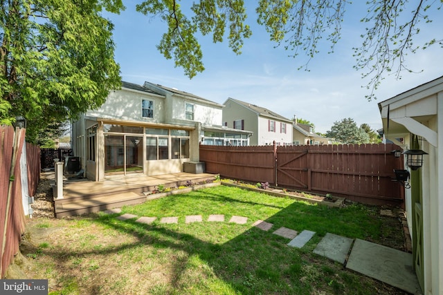 view of yard with a fenced backyard, a gate, a wooden deck, a sunroom, and cooling unit
