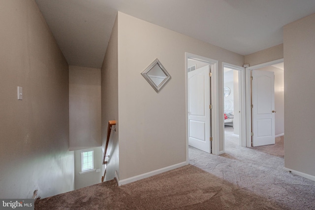 corridor featuring baseboards, visible vents, and carpet