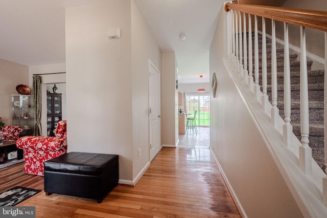 hall with stairs, baseboards, and light wood-style floors