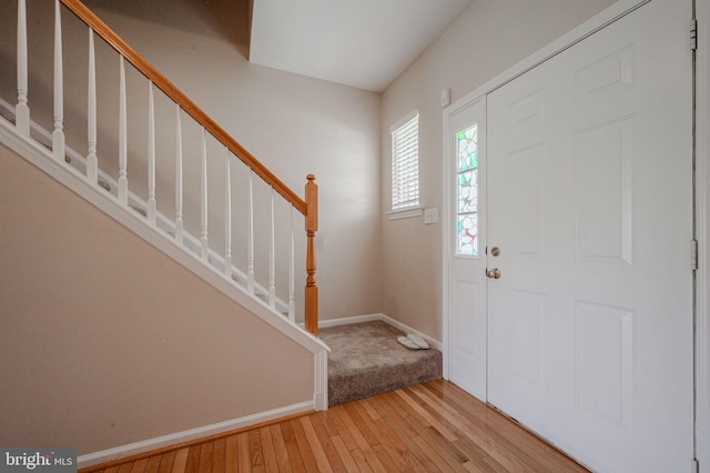 foyer entrance with baseboards, light wood-style flooring, and stairs