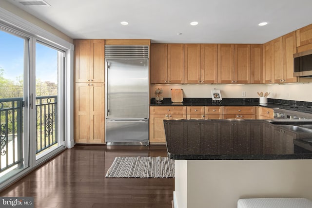 kitchen with dark stone counters, dark wood-style floors, recessed lighting, and appliances with stainless steel finishes