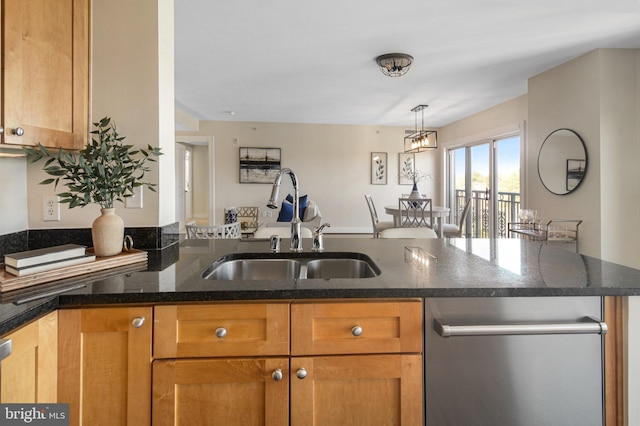 kitchen featuring a peninsula, stainless steel dishwasher, a sink, dark stone counters, and decorative light fixtures