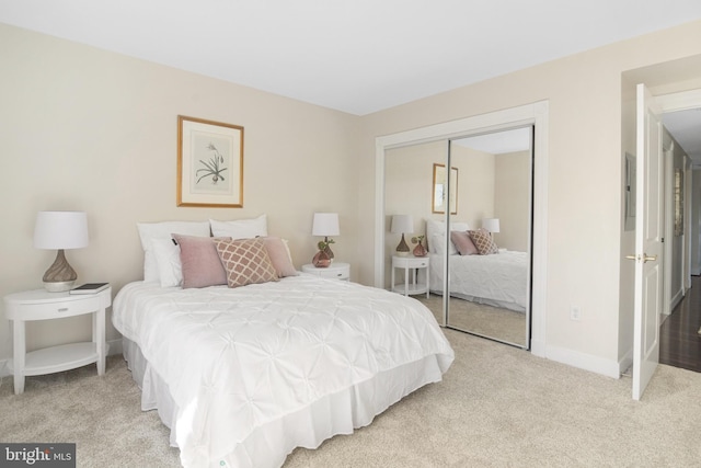 bedroom featuring baseboards, a closet, and light colored carpet