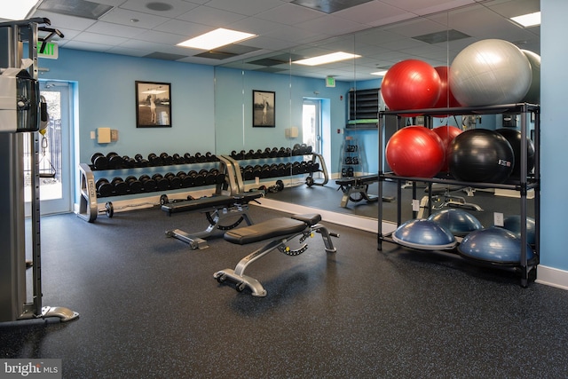 exercise room featuring a drop ceiling and baseboards
