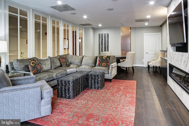 living area featuring dark wood-style flooring, a glass covered fireplace, visible vents, and recessed lighting