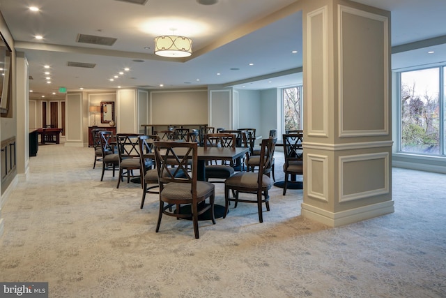 dining area featuring light colored carpet, a wealth of natural light, and a decorative wall
