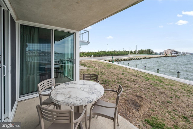 balcony with outdoor dining area and a water view