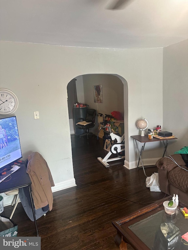 interior space featuring arched walkways, baseboards, and wood finished floors