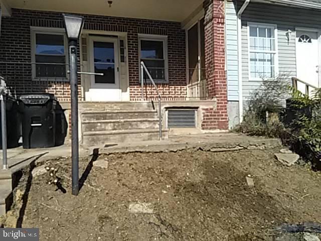 view of exterior entry with brick siding and covered porch