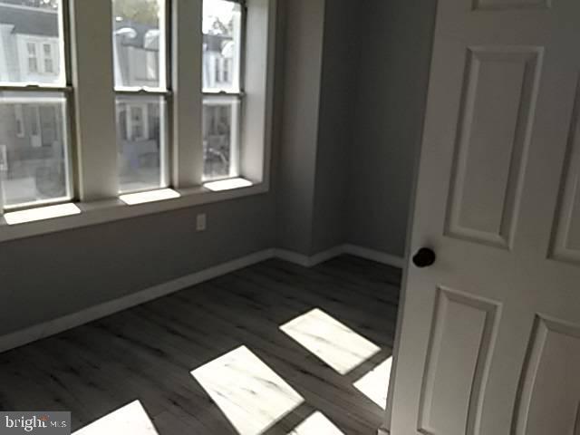 empty room with wood finished floors, baseboards, and plenty of natural light