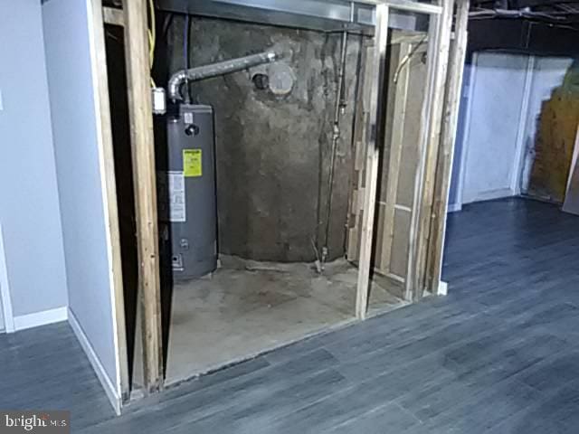 unfinished below grade area featuring water heater and wood finished floors