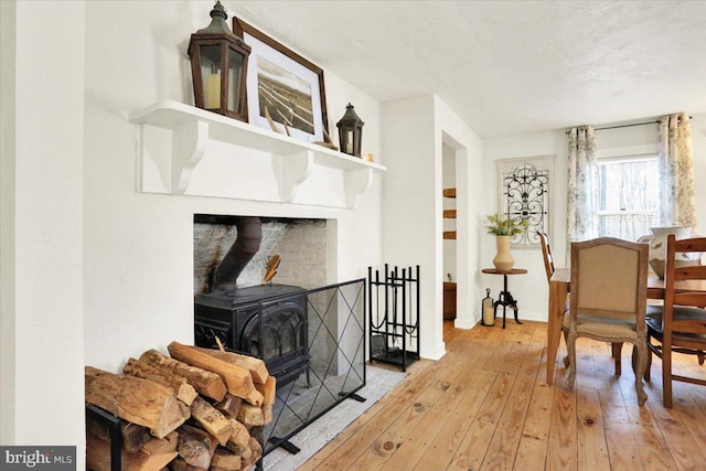 living area with baseboards, a wood stove, and wood-type flooring