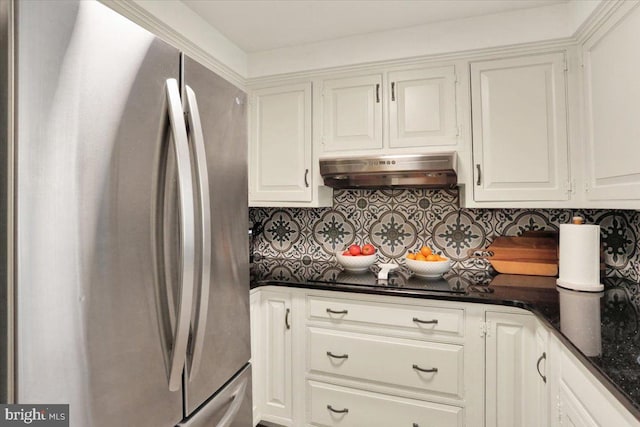 kitchen with decorative backsplash, black electric stovetop, white cabinets, under cabinet range hood, and freestanding refrigerator