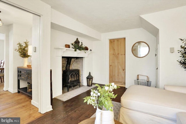 living room featuring baseboards, a wood stove, and hardwood / wood-style flooring