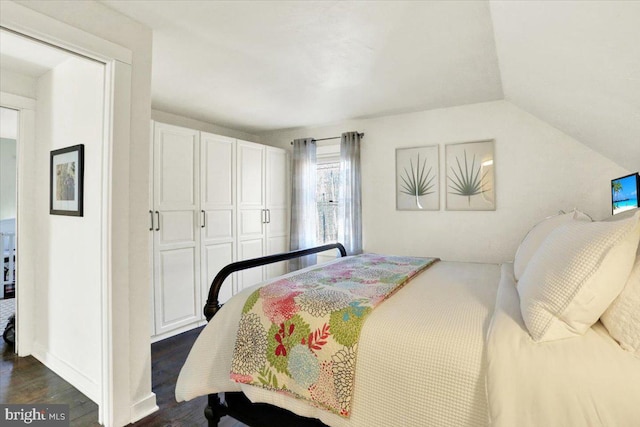 bedroom with vaulted ceiling and dark wood-style floors