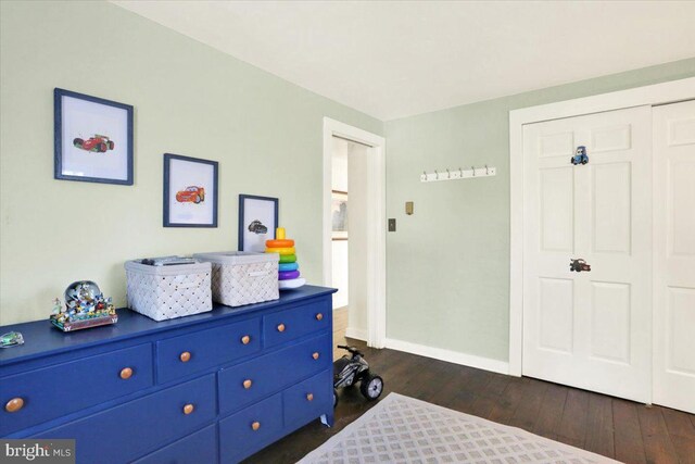 bedroom with baseboards, a closet, and dark wood finished floors