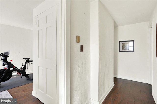 hallway with baseboards and dark wood-style flooring