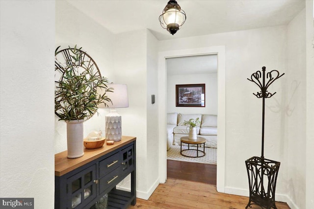 hallway featuring wood-type flooring and baseboards